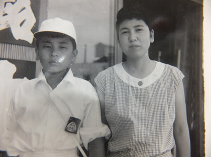 「自宅の銘木店の前で、母親と」